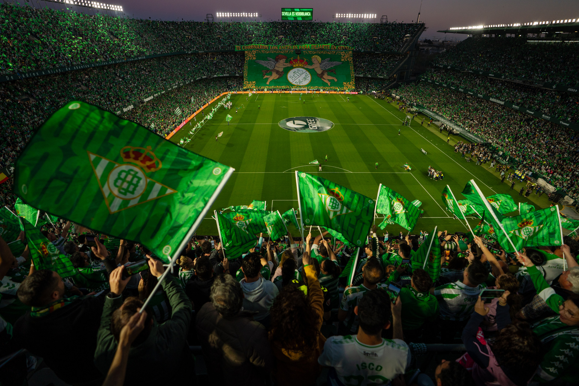 Supporters waving green-and-white Real Betis flags inside the Benito Villamarín stadium in Heliópolis.